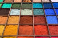 Wooden trays display brightly colored mineral pigment powders and crystals