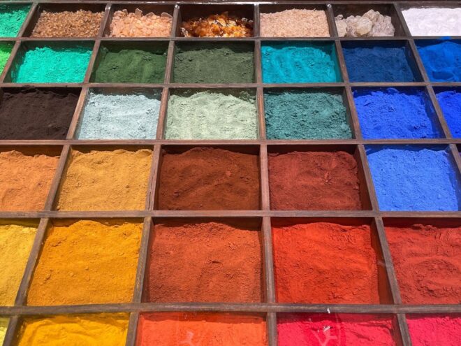 Wooden trays display brightly colored mineral pigment powders and crystals