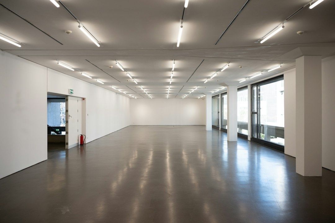 Empty white-cube gallery with polished floor and large windows